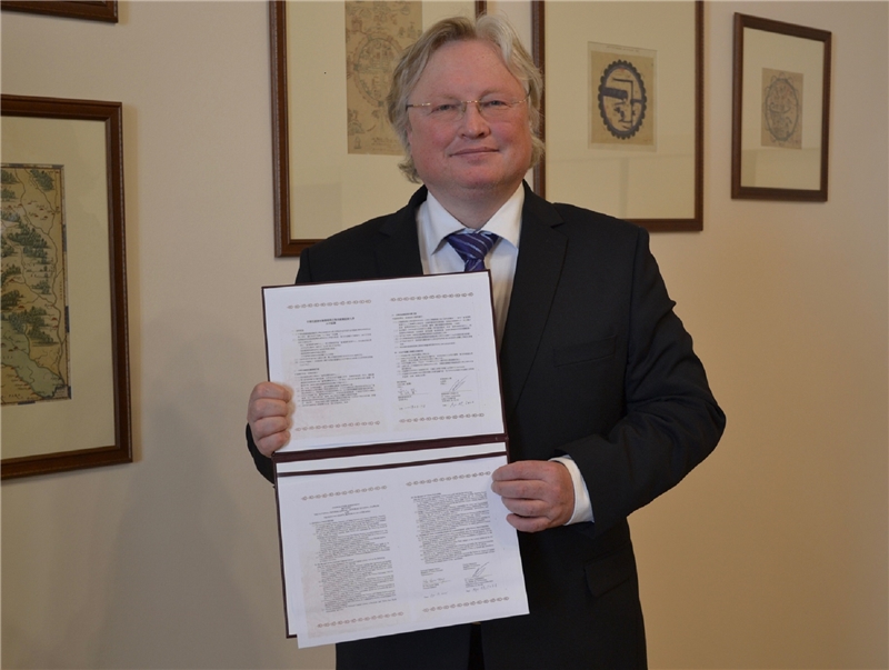 維爾紐斯大學副校長Artūras Vasiliauskas手持合作協議書。
